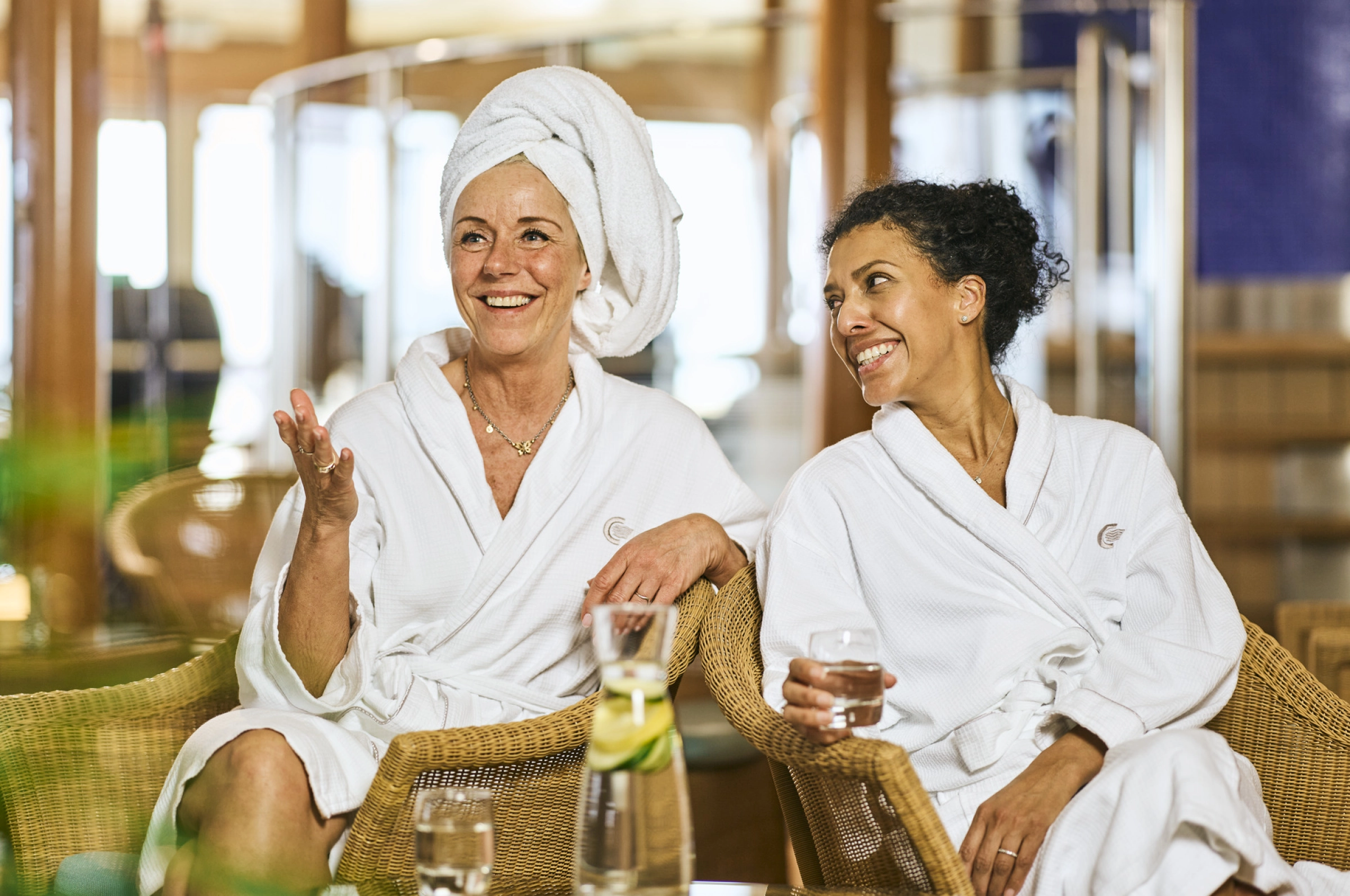 To damer i badekåpe slapper av i spaets lounge
